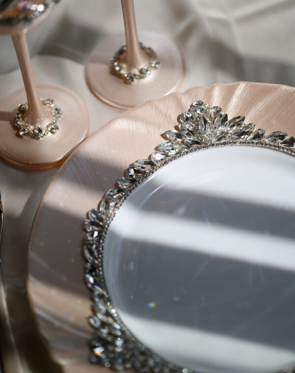 Close-up detail of Grace Classic rose gold plate with dimensional crystal floral border and champagne flute bases embellished with clear crystals