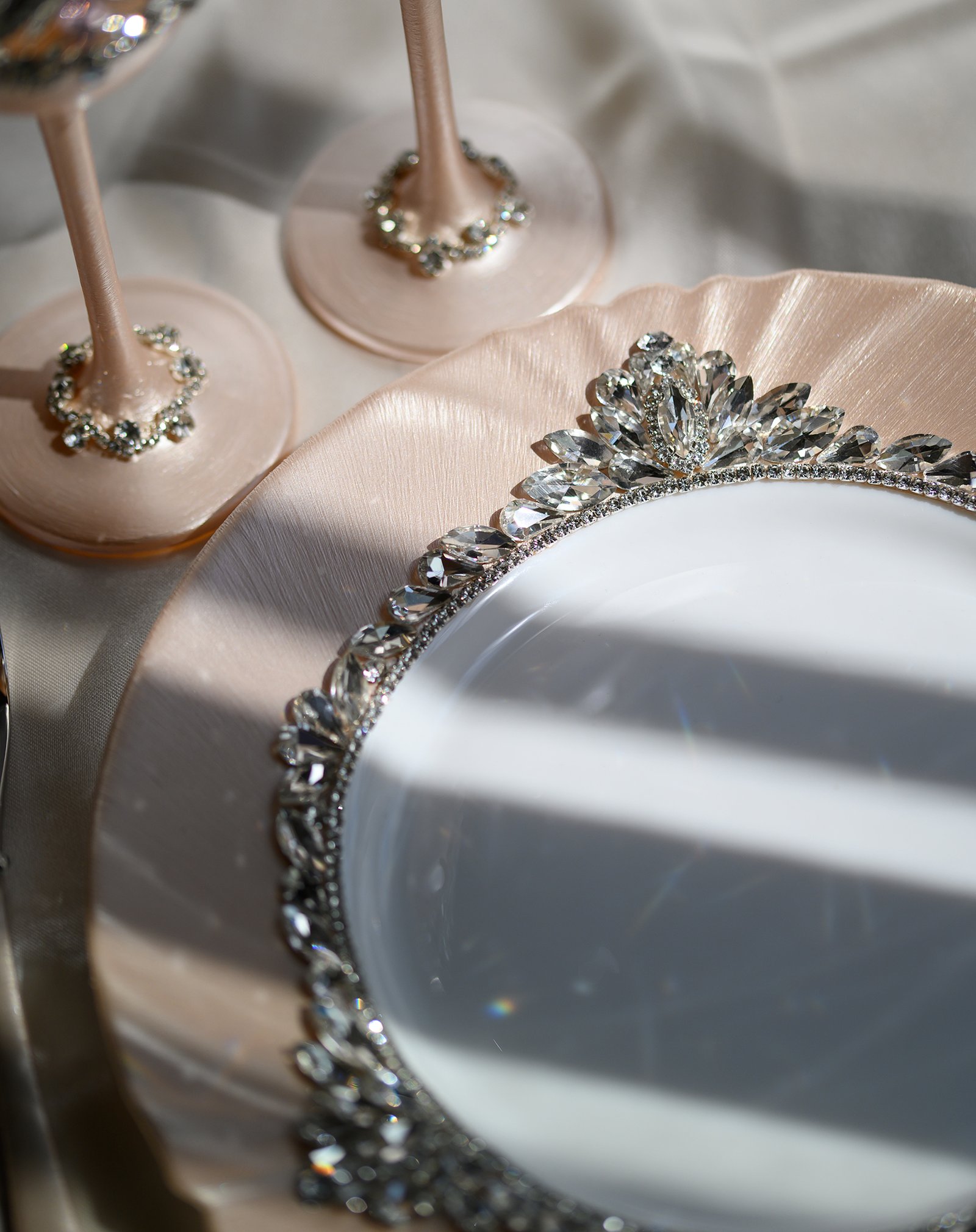 Close-up detail of Grace Classic rose gold plate with dimensional crystal floral border and champagne flute bases embellished with clear crystals