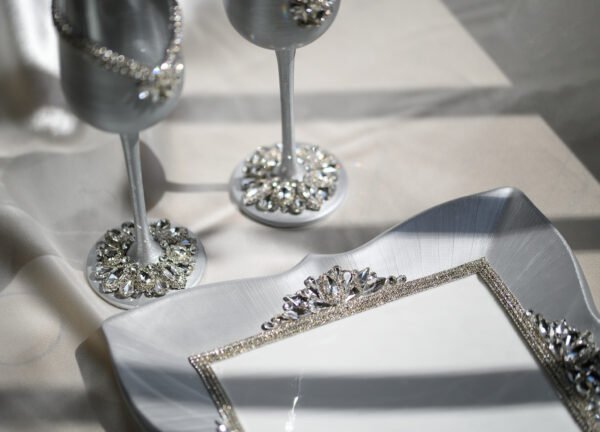 Close-up detail of Majestic Classic luxury wedding set showing silver crystal-embellished champagne flutes and handpainted silver plate with crystal fork accents