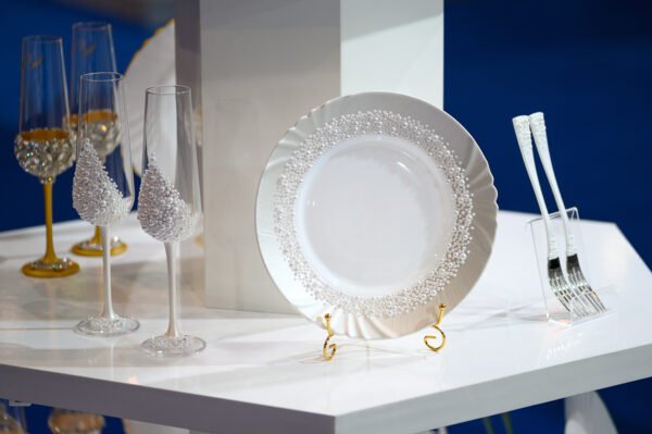 Pearl Classic handcrafted luxury wedding set featuring white pearl-encrusted champagne flutes, handpainted white plate with pearl border, and elegant white pearl-adorned forks on display