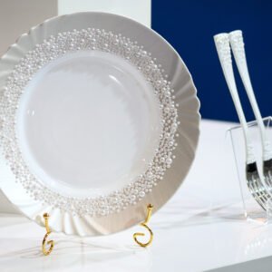 Pearl Classic handpainted white plate with densely arranged pearl border and scalloped edge, displayed on gold stand with matching white pearl-adorned forks against navy blue background