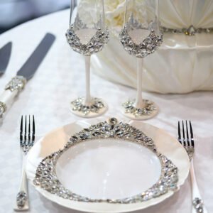Crystal-embellished champagne flutes and matching dinnerware from Ethereal collection with white wedding cake
